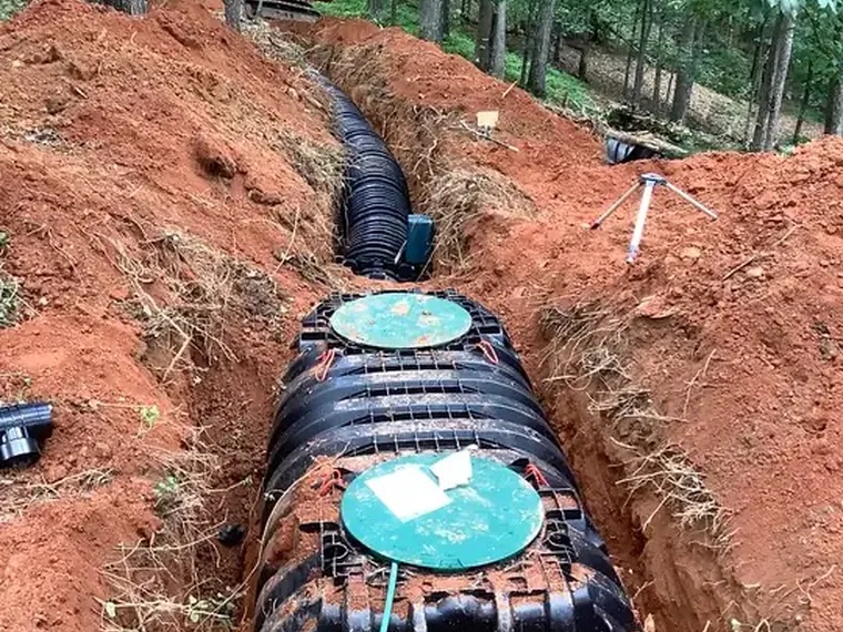 New septic tank and drain field set in an excavated trench during a full system replacement
