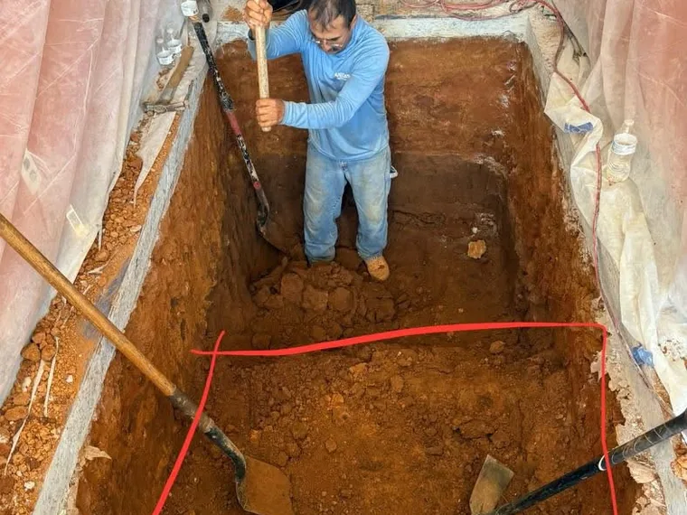 SepticRooter technician hand-excavating inside a saw-cut interior slab for a commercial grease trap