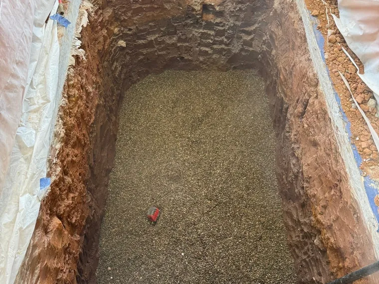 Deep interior excavation with a leveled gravel base ready for a grease trap