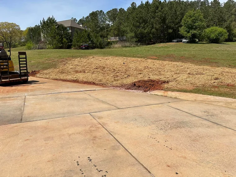 Close-up of repaired and re-seamed concrete driveway sections with SepticRooter technician working in background